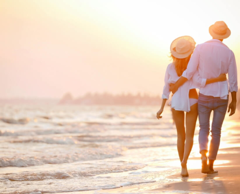 A couple walking on the beach during their romantic getaway to Tybee Island.